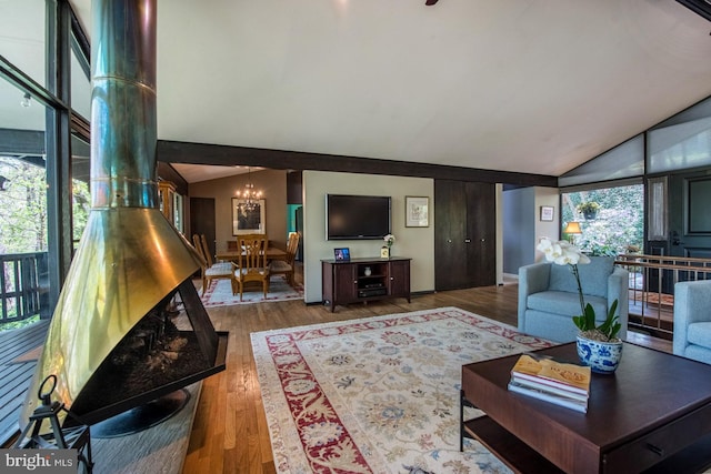 living room with wood finished floors, baseboards, a chandelier, and lofted ceiling
