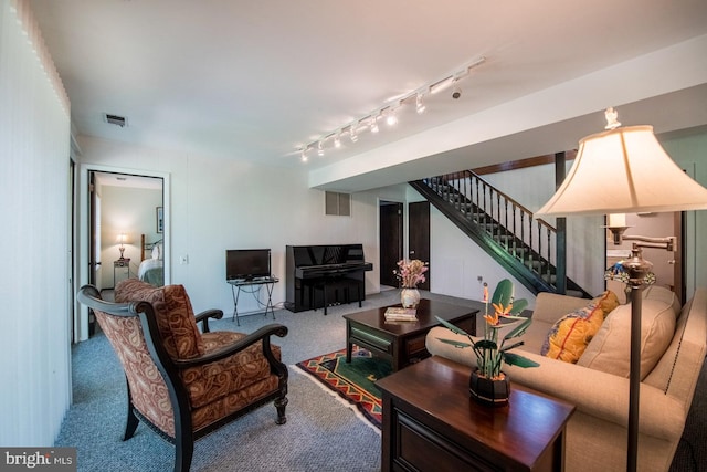 living area featuring carpet floors, visible vents, track lighting, and stairway
