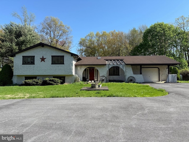 split level home with a front yard, stucco siding, driveway, and an attached garage