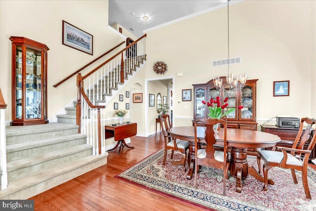 dining space with visible vents, an inviting chandelier, hardwood / wood-style floors, baseboards, and stairway