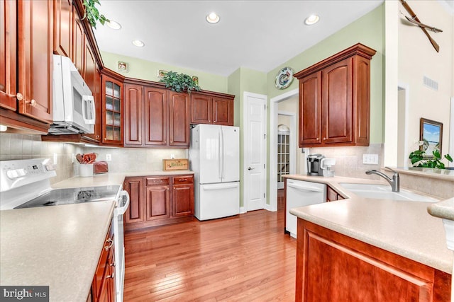 kitchen with tasteful backsplash, glass insert cabinets, light wood-style floors, recessed lighting, and white appliances