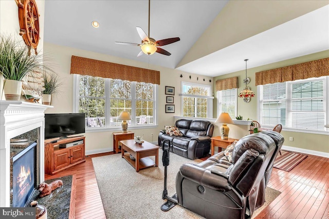 living area featuring a wealth of natural light, a premium fireplace, a ceiling fan, and hardwood / wood-style flooring