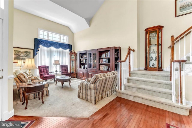 living room with baseboards, high vaulted ceiling, stairs, and wood-type flooring
