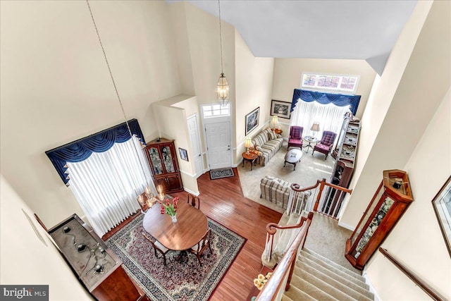 living room featuring high vaulted ceiling, stairway, wood finished floors, and baseboards
