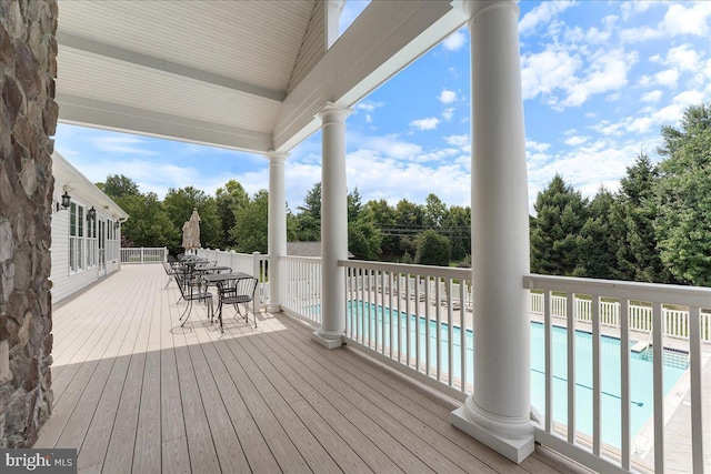 wooden terrace with fence, outdoor dining area, and a fenced in pool