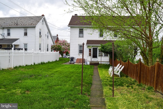 back of house featuring fence, a yard, and entry steps