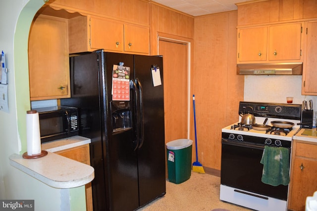 kitchen with black appliances, light countertops, arched walkways, and under cabinet range hood