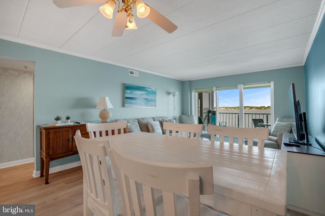 dining area featuring wood finished floors, a ceiling fan, visible vents, baseboards, and ornamental molding