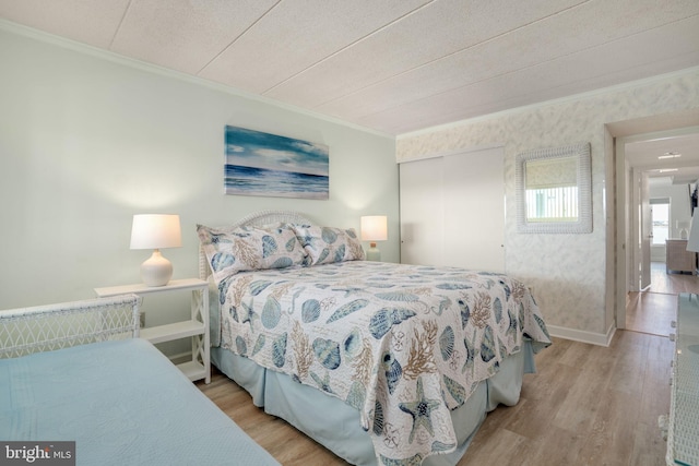 bedroom with ornamental molding, a closet, wallpapered walls, and wood finished floors