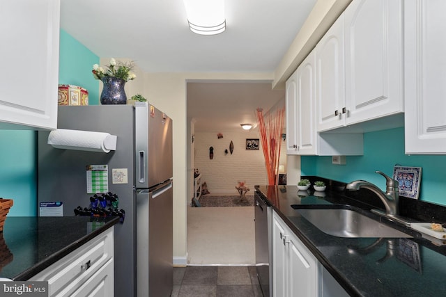 kitchen featuring dark stone counters, a sink, stainless steel appliances, white cabinetry, and dark tile patterned floors