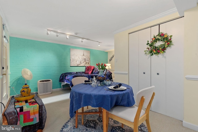 carpeted dining area with track lighting, ornamental molding, and baseboards