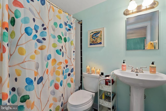 bathroom with curtained shower, toilet, and a sink