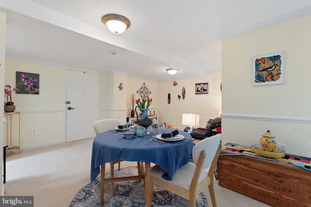 dining area with baseboards, ornamental molding, and light carpet