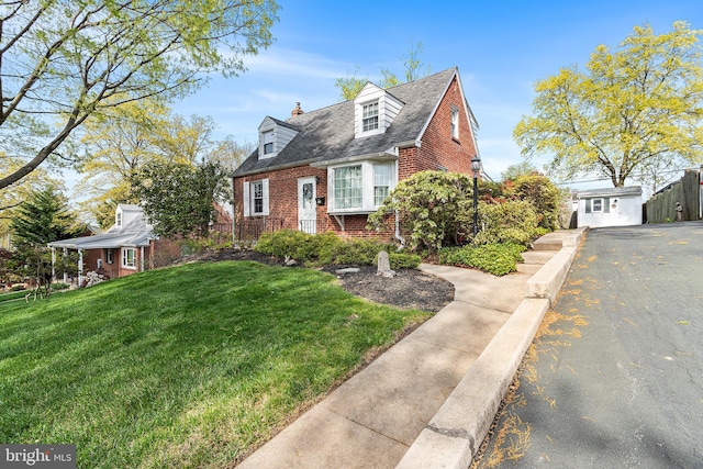 cape cod house featuring a chimney, a front yard, aphalt driveway, and brick siding