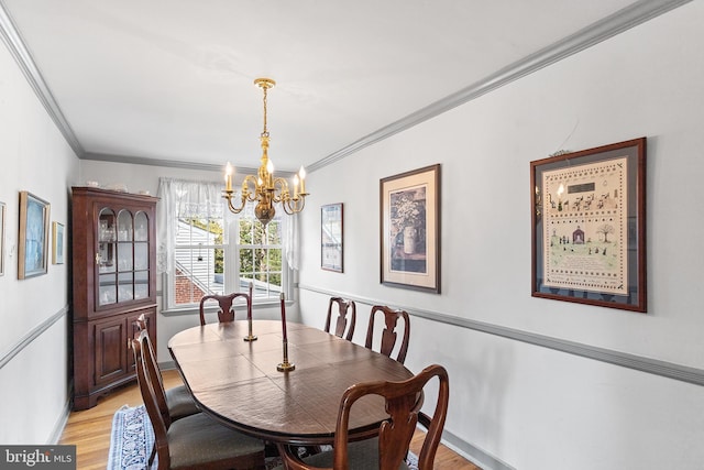 dining area featuring an inviting chandelier, light wood finished floors, crown molding, and baseboards