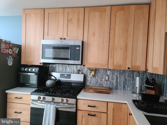 kitchen featuring stainless steel appliances, backsplash, light brown cabinets, and light countertops