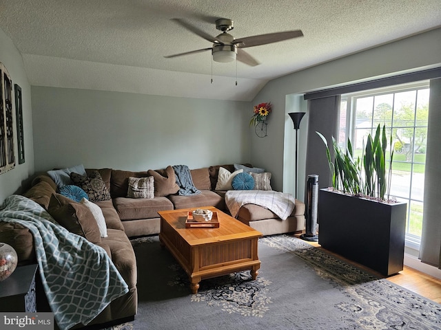 living room with a ceiling fan, wood finished floors, lofted ceiling, and a textured ceiling