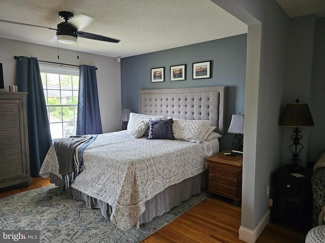 bedroom with a textured ceiling, wood finished floors, and a ceiling fan