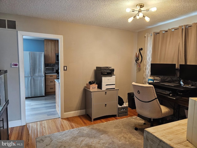 office area featuring wood finished floors, an inviting chandelier, a toaster, visible vents, and a textured ceiling