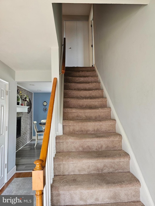 stairway featuring a fireplace, wood finished floors, and baseboards