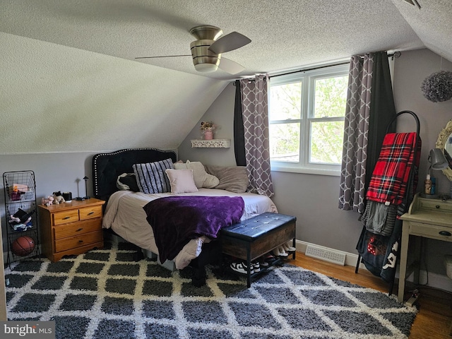 bedroom with a ceiling fan, visible vents, vaulted ceiling, a textured ceiling, and wood finished floors