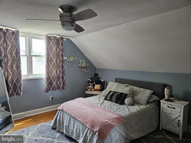 bedroom with ceiling fan, visible vents, baseboards, a textured ceiling, and wood finished floors