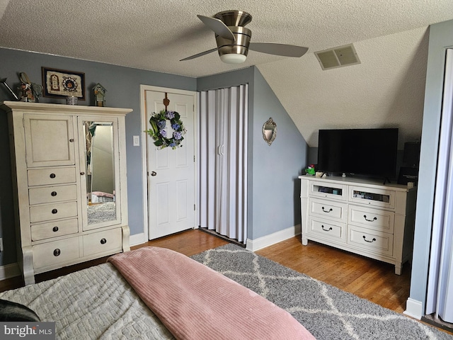 bedroom with baseboards, visible vents, wood finished floors, and a textured ceiling