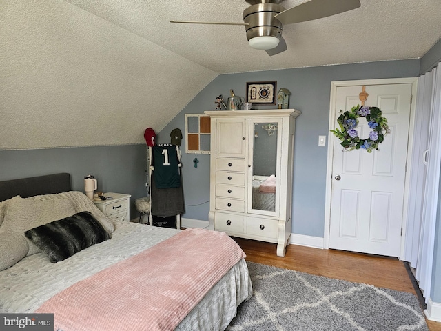 bedroom with baseboards, wood finished floors, a textured ceiling, and lofted ceiling