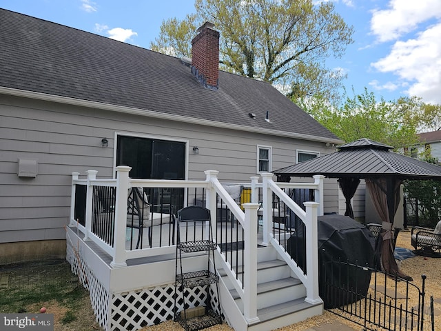 rear view of property with a chimney, a gazebo, a wooden deck, and roof with shingles