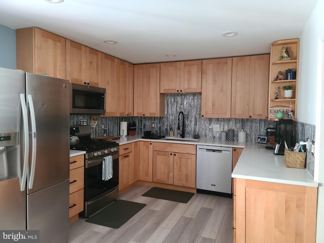 kitchen featuring decorative backsplash, light wood-style floors, appliances with stainless steel finishes, light countertops, and a sink