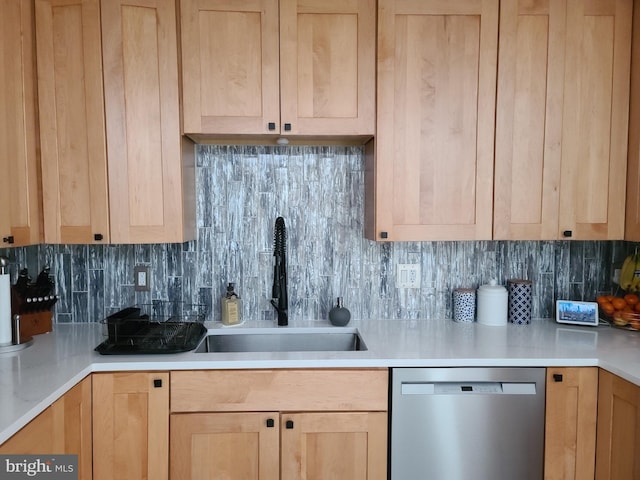 kitchen featuring stainless steel dishwasher, a sink, tasteful backsplash, and light brown cabinets