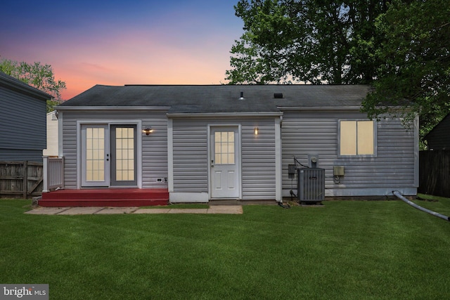 2963 Crystal Palace Ln, Pasadena, MD 21122 - back of property at dusk featuring central AC, roof with shingles, fence, and a yard