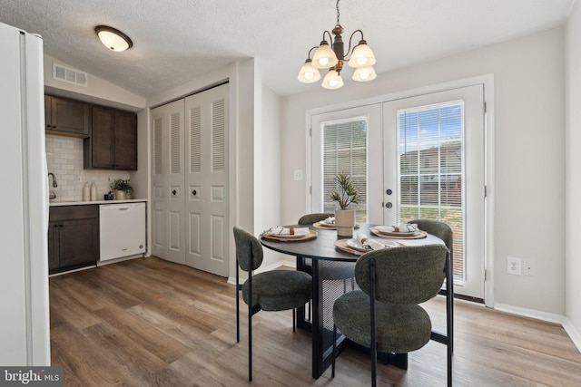 2963 Crystal Palace Ln, Pasadena, MD 21122 - dining room featuring french doors, a textured ceiling, visible vents, a notable chandelier, and light wood-style flooring