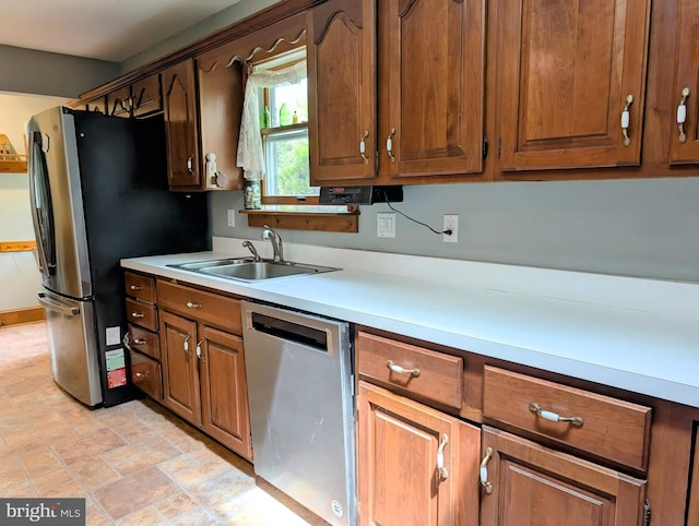 kitchen featuring a sink, appliances with stainless steel finishes, stone finish flooring, and light countertops
