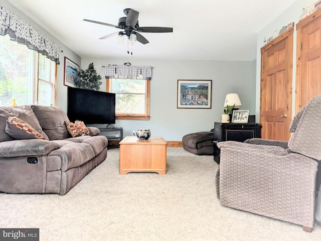living area featuring carpet floors, baseboards, and a ceiling fan