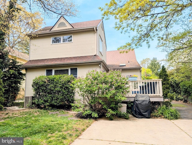 exterior space featuring a lawn, roof with shingles, and a wooden deck