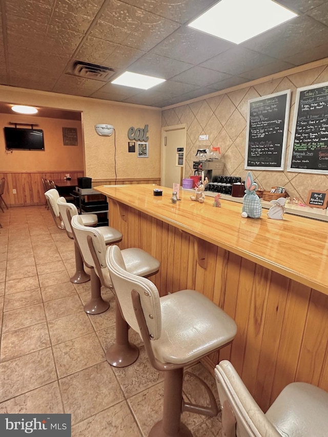 bar with wooden walls, visible vents, and light tile patterned floors