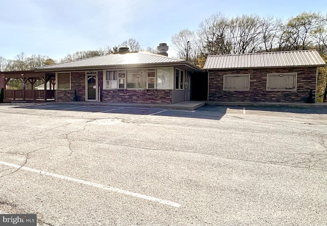 view of front facade featuring a chimney, metal roof, and stone siding