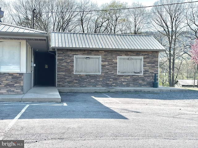 exterior space featuring metal roof and stone siding