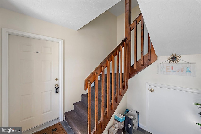 stairs featuring a textured ceiling