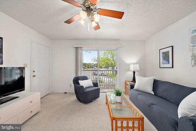 living area featuring a ceiling fan, a textured ceiling, light carpet, and baseboards