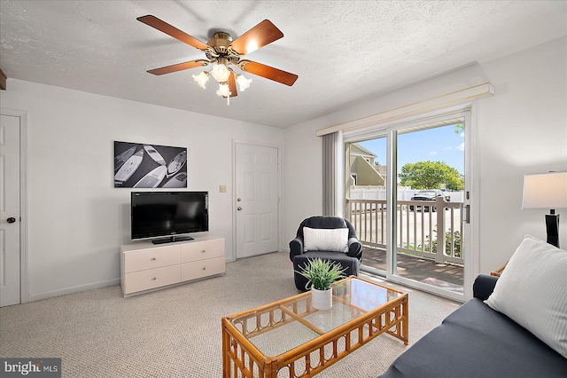 carpeted living area with baseboards, a ceiling fan, and a textured ceiling