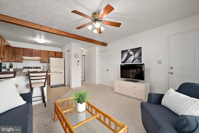living room with a textured ceiling, ceiling fan, beam ceiling, and light carpet