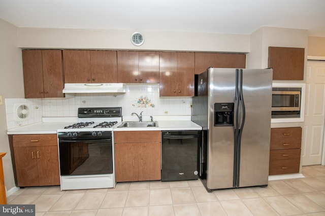 kitchen with a sink, appliances with stainless steel finishes, light countertops, under cabinet range hood, and backsplash