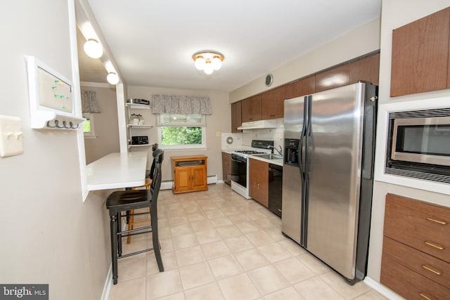 kitchen featuring brown cabinets, stainless steel appliances, light countertops, baseboard heating, and under cabinet range hood