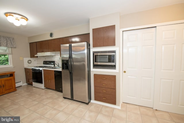 kitchen featuring stainless steel appliances, under cabinet range hood, tasteful backsplash, light countertops, and baseboard heating