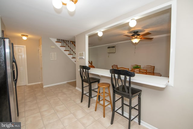 dining space featuring a wall mounted AC, a ceiling fan, baseboards, and stairs