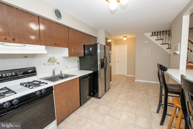 kitchen featuring decorative backsplash, under cabinet range hood, dishwasher, a sink, and range with gas cooktop