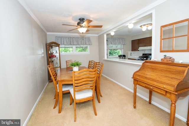 dining room with light colored carpet, a ceiling fan, crown molding, and baseboards