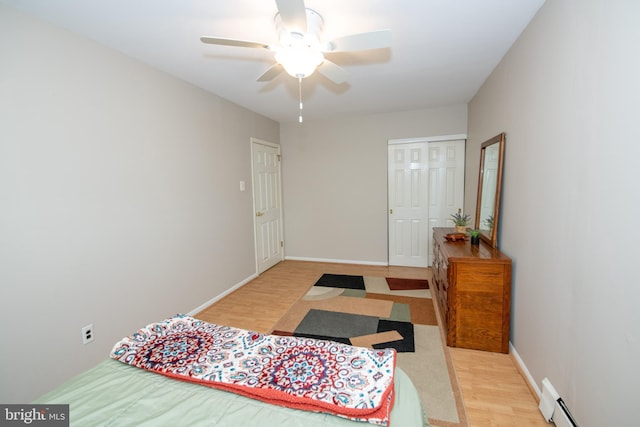 bedroom featuring baseboard heating, baseboards, wood finished floors, and ceiling fan